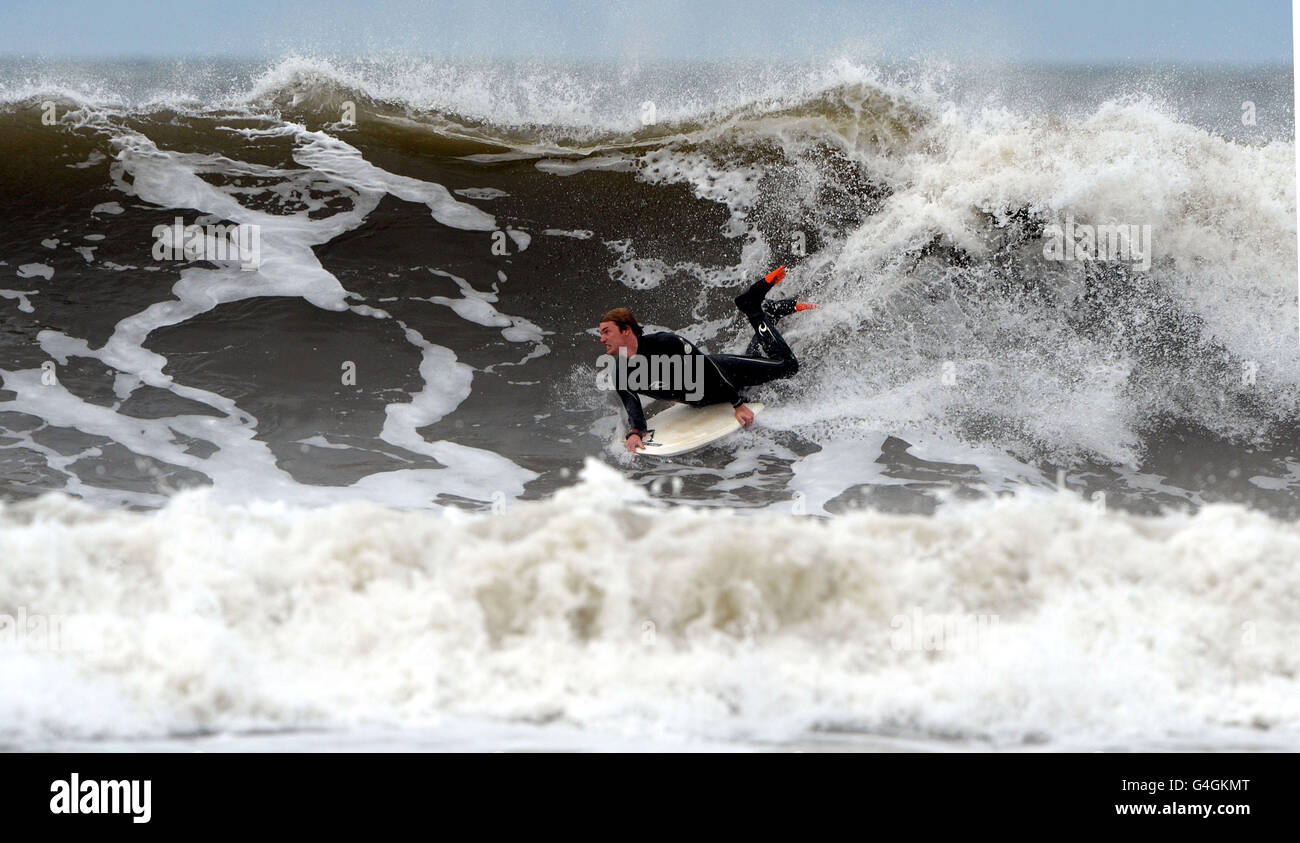 A body boarder enjoys the large swell on Tynemouth beach, as the unsettled weather produced large waves on the coast of the north east of England. Stock Photo
