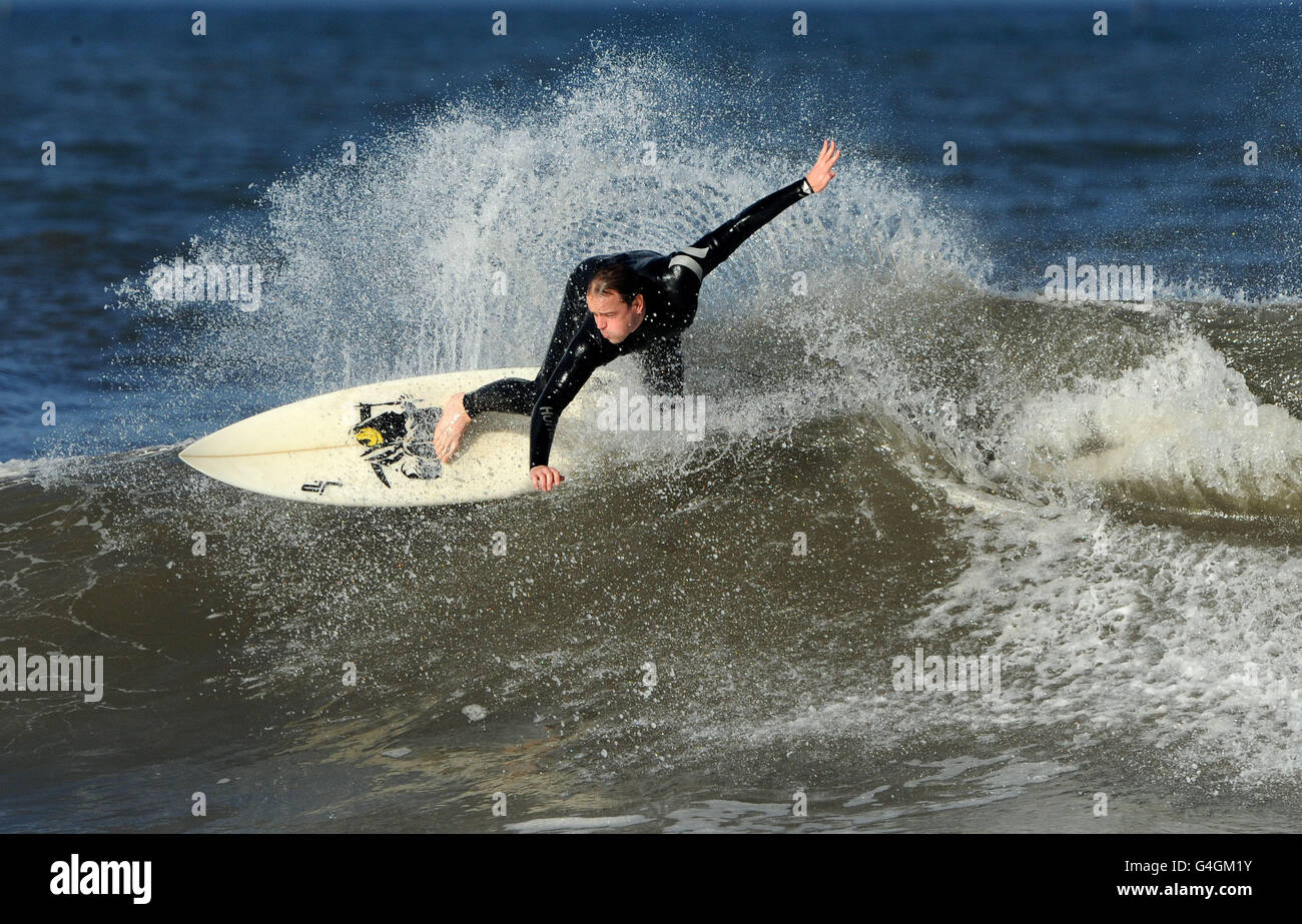Surfing on Tynemouth beach. A surfer enjoys an evening surf in the large swell on Tynemouth beach this evening. Stock Photo