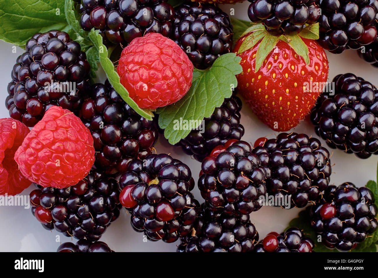 Heap of blackberries, strawberries and raspberries with mint leaves Stock Photo