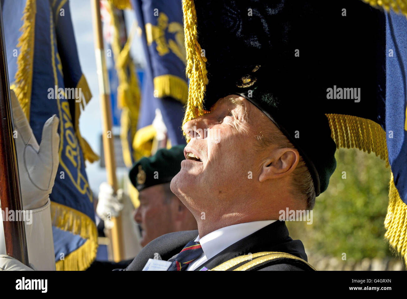 A British Legion Standard Bearer looks at his flag as he raises it after the cortege of Royal Marine Sergeant Barry Weston, of 42 Commando, who was killed by a roadside bomb while on patrol in Helmand Province passes the Royal British Legion Standard Bearers, people from Brize Norton village and Ex-Royal Marine veterans en route to John Radcliffe hospital. Stock Photo