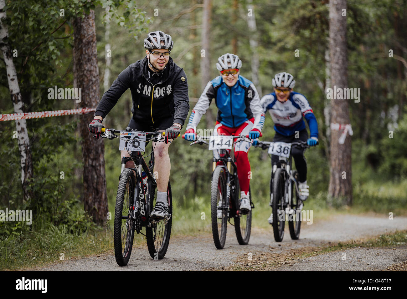 group of male cyclists riding through forest during cross-country race 'New energy' Stock Photo