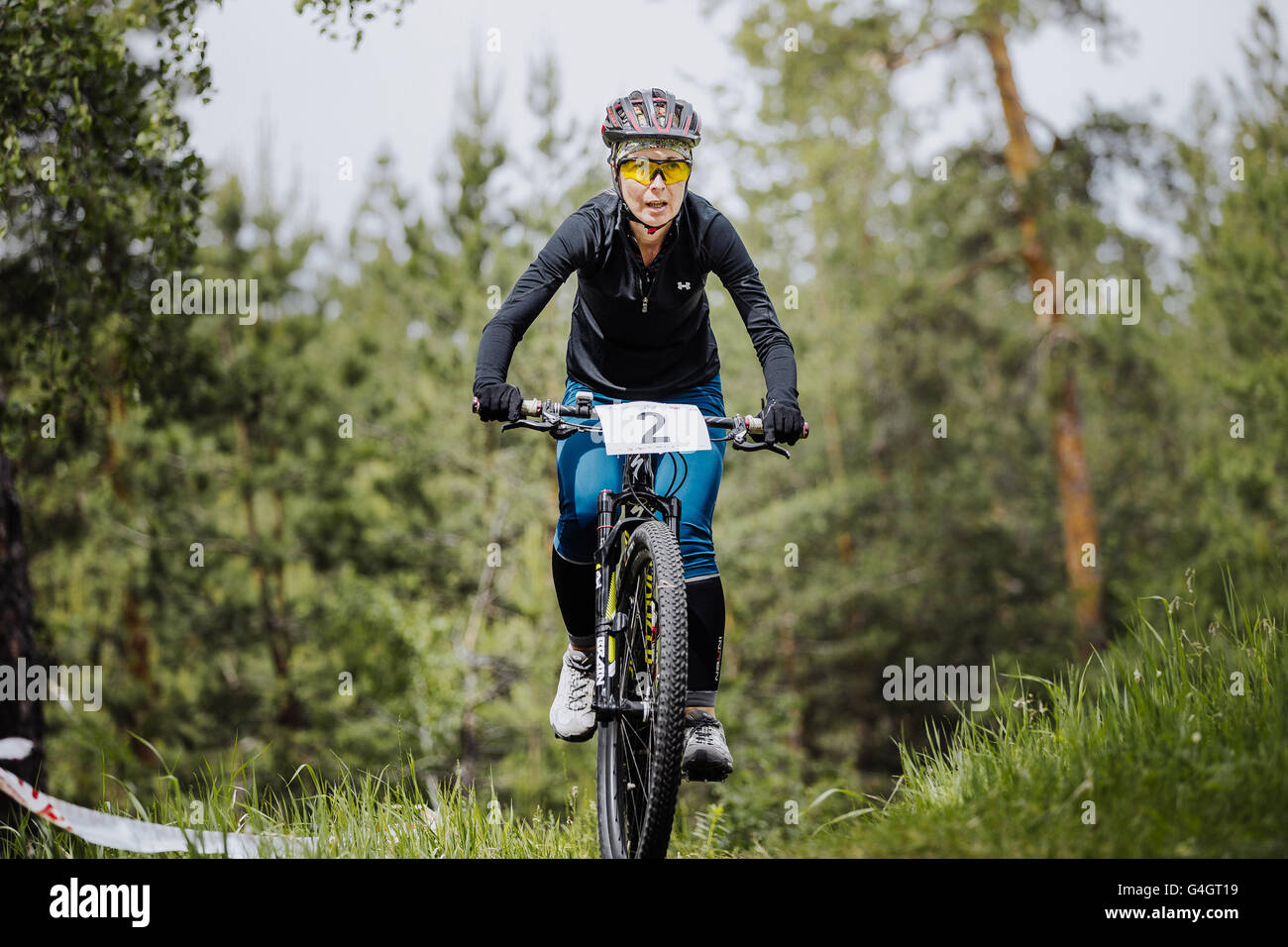 young girl athlete cyclist rides through forest during cross-country race 'New energy' Stock Photo