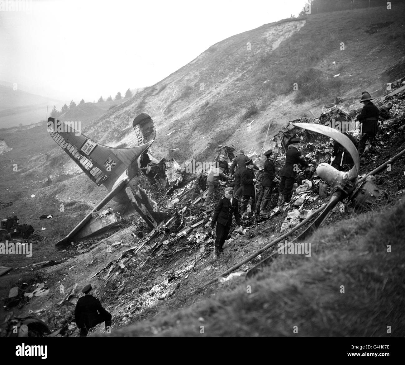 Between the severed tail unit and a twisted propeller, searchers hunt for bodies amid the wreckage of the Aquila Airways double deck flying boat that crashed on the slopes of a chalk pit on the Isle of Wright and burst into flames. Stock Photo