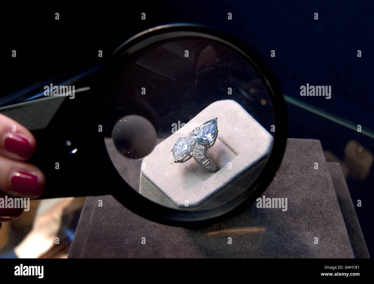 A Bonham's employee takes a closer look through a magnifying glass at a diamond and blue diamond crossover ring, by Bulgari, circa 1960, which is estimated to fetch 600,000 to 800,000, at Bonham's in London. Stock Photo