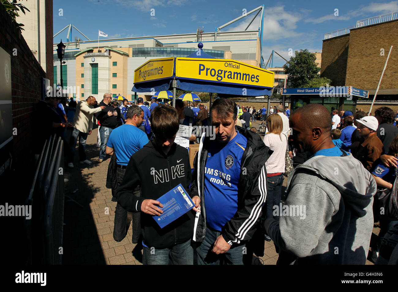 Fans buy matchday programmes at Stamford Bridge before the match Stock ...