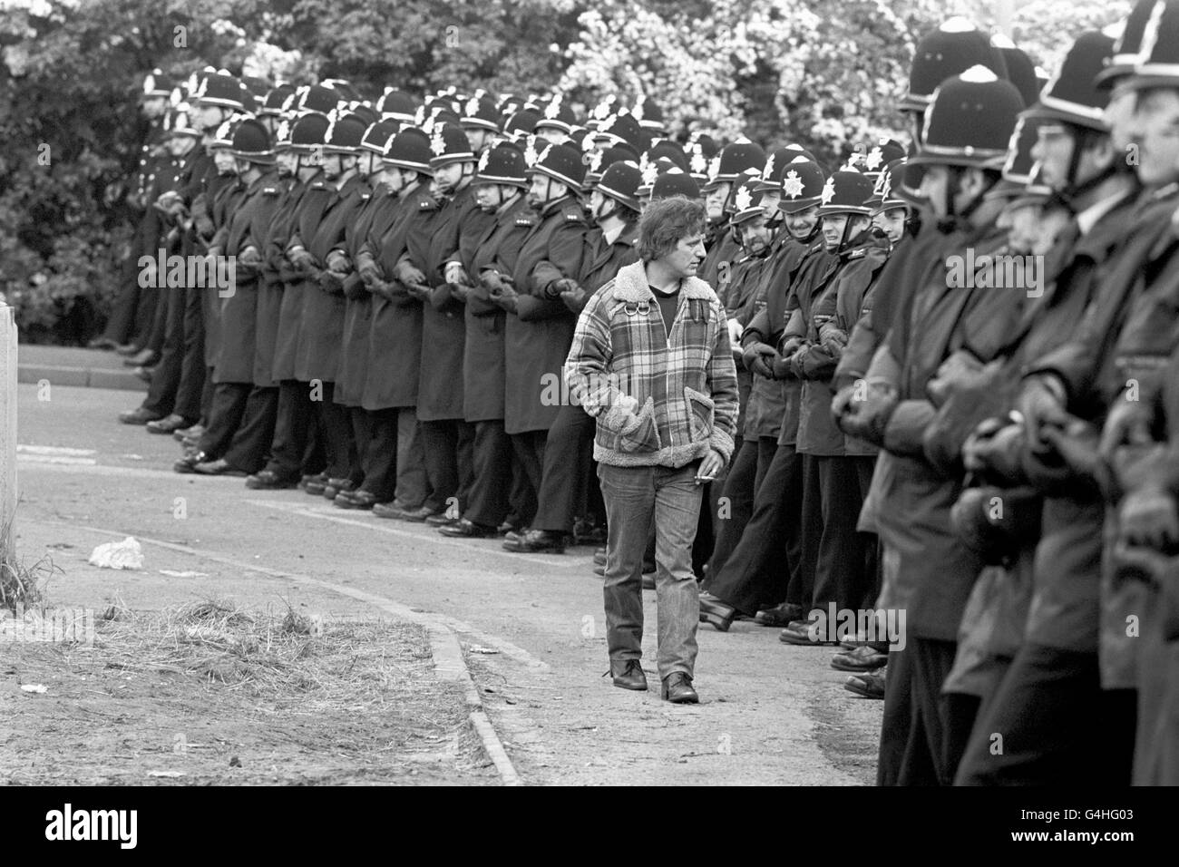A CHEEKY PICKET CALMLY 'INSPECTS' A LINE OF LINKED POLICEMAN OUTSIDE THE ORGREAVE COKING PLANT NEAR ROTHERHAM DURING THE MINERS DISPUTE. Stock Photo
