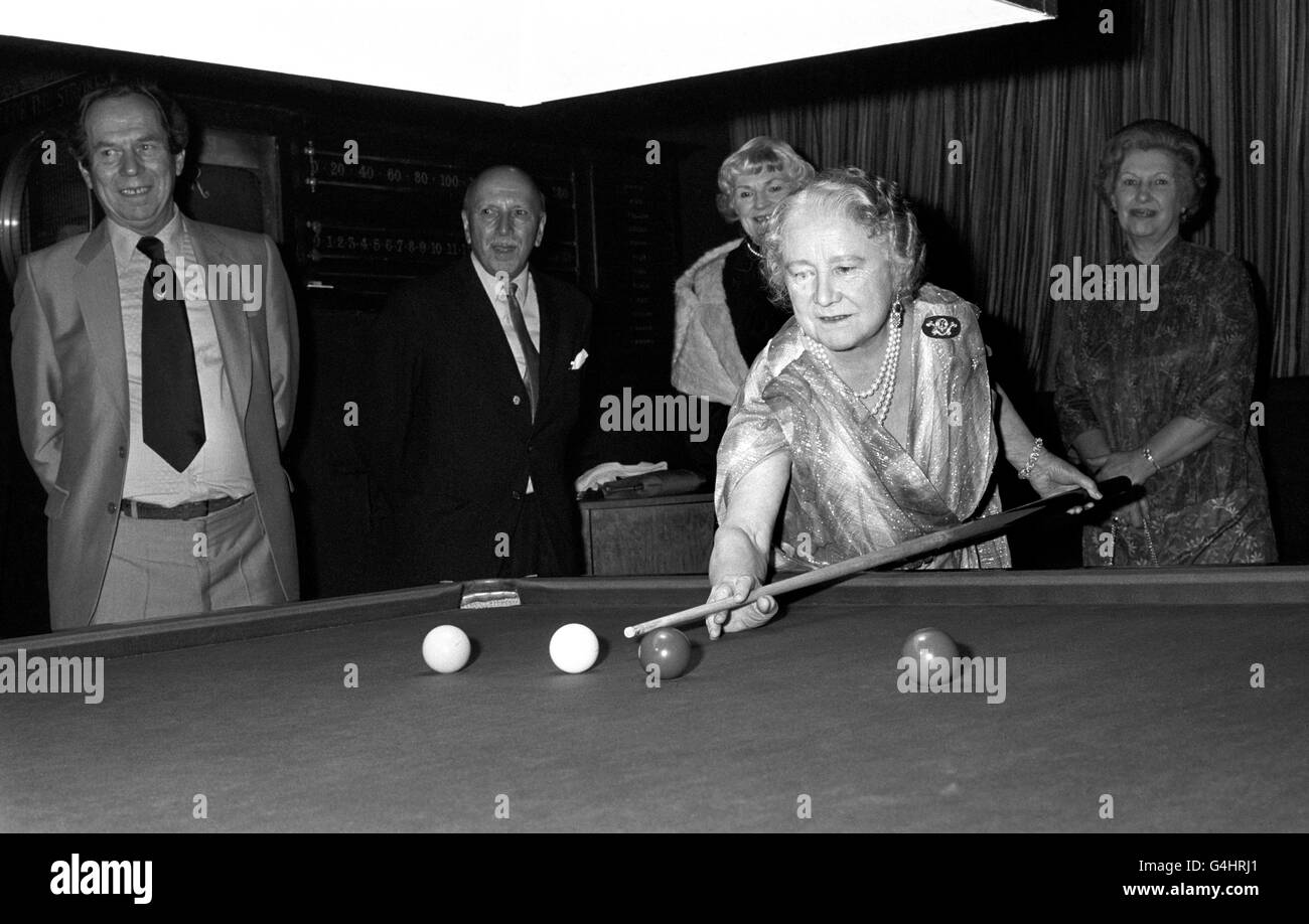 As part of her 80th birthday celebration, the Queen Mother visited the Press Club, Shoe Lane, London, where she tried her skill on the snooker table, watched by Secretary John Le Neve, left. Stock Photo