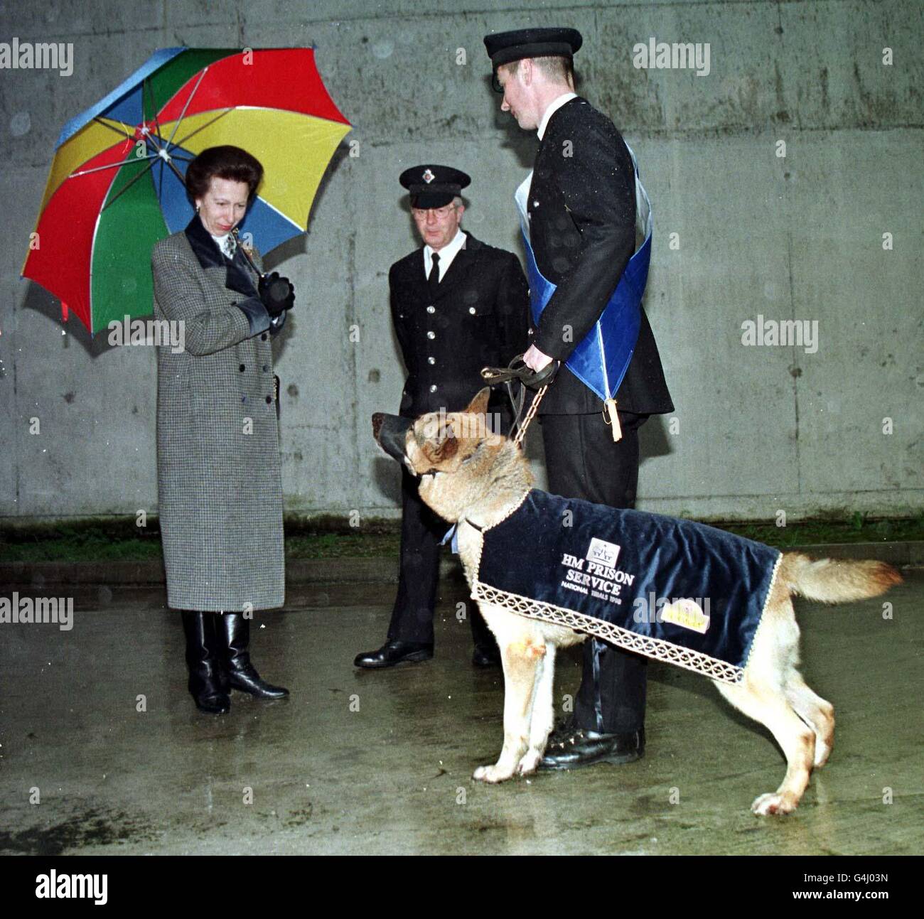 The Princess Royal kept a designated three feet away from Tyson, Britain's toughest prison dog, when she visited Her Majesty's Prison Manchester, formerly Strangeways. Tyson's handler Simon Broadist is on the right. Stock Photo