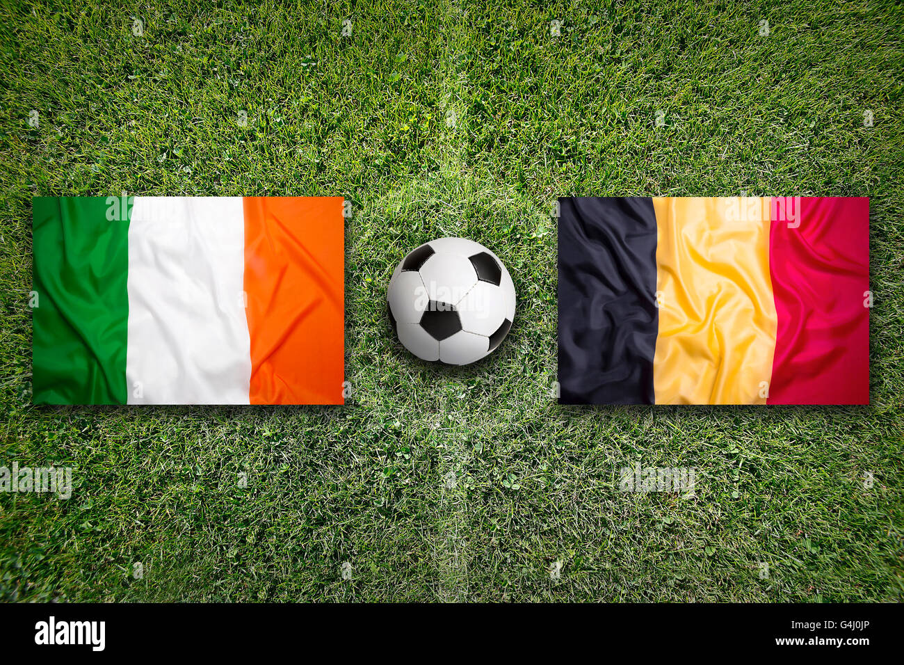 Ireland vs. Belgium flags on green soccer field Stock Photo