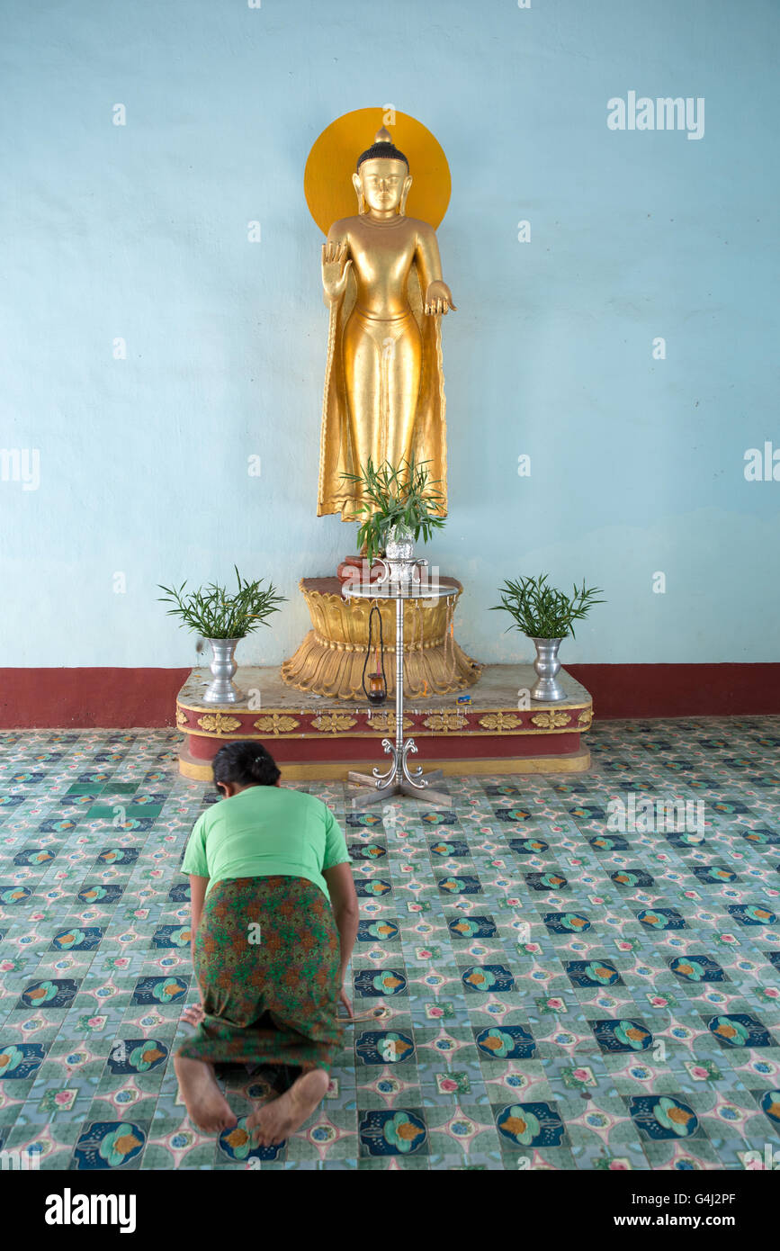 A believer bowing in front of a standing Buddha statue, Shwezigon Pagoda, Nyanung-U, Mandalay Region, Myanmar Stock Photo