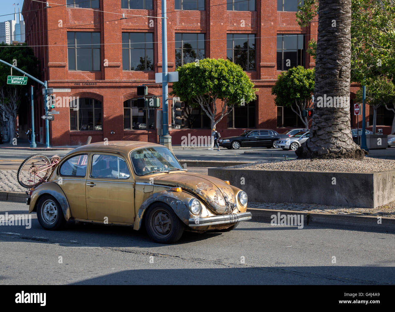 Old gold volkswagon beetle driving down Stock Photo