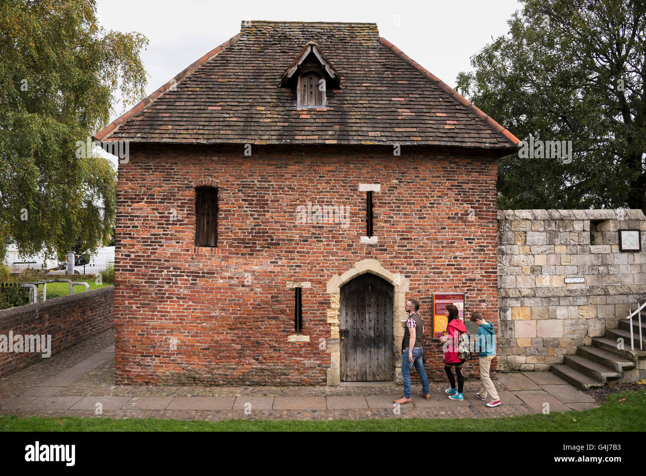 Family of 3 tourists standing by entrance door to C15 Red Tower & medieval city walls - historic attractions in York, North Yorkshire, England, UK. Stock Photo