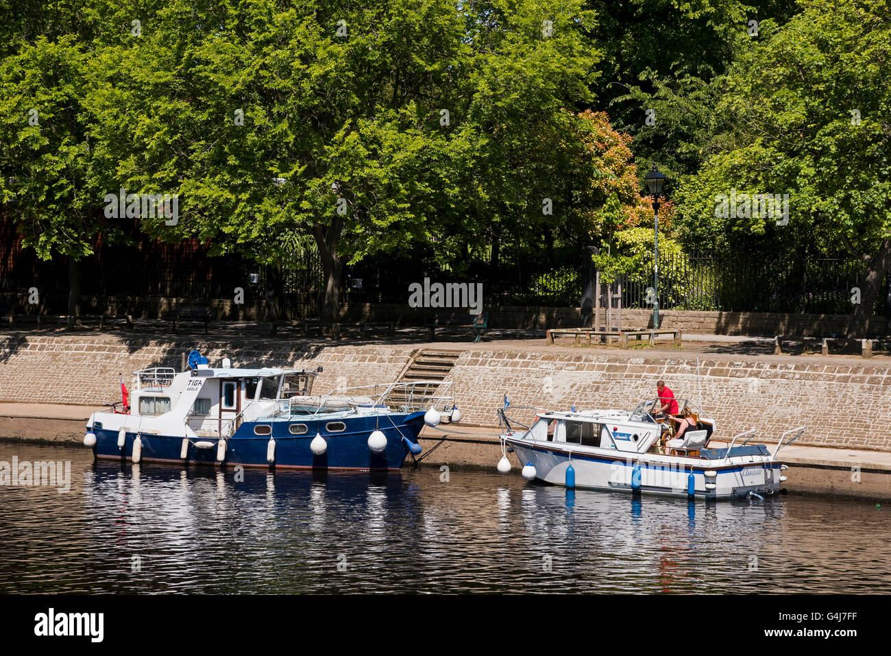 Couple aboard one of 2 river cruiser boats moored on the banks of the River Ouse, York, North Yorkshire, GB, on a sunny day. Stock Photo