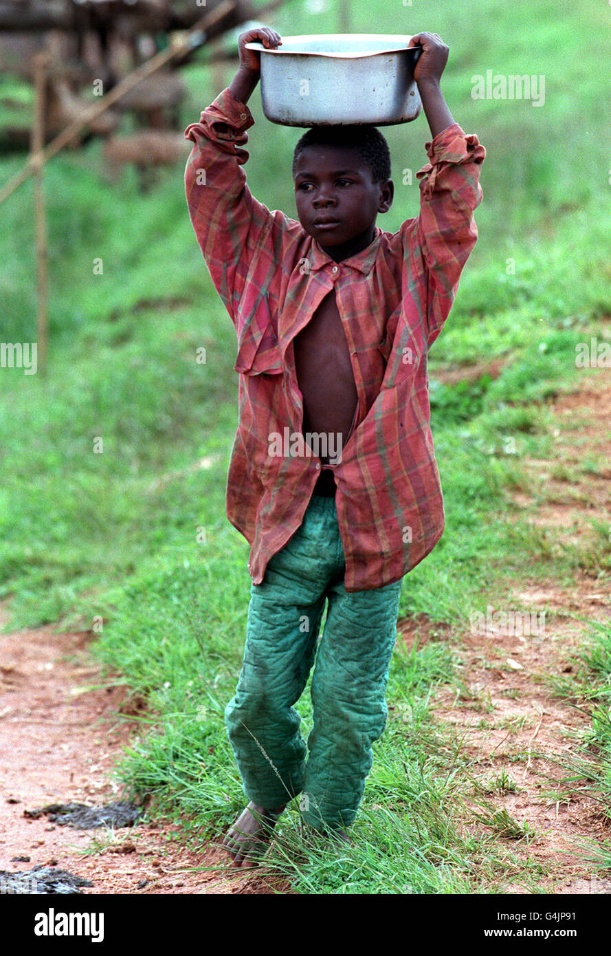 A yong boy carries a metal basin on his head in Njombe Town, Tanzania. The picture was taken during Melanie Clark Pullen's (Mary in Eastenders) trip to East Africa, to highlight the Jubilee 2000 Campaign to cancel Third World debt. Stock Photo