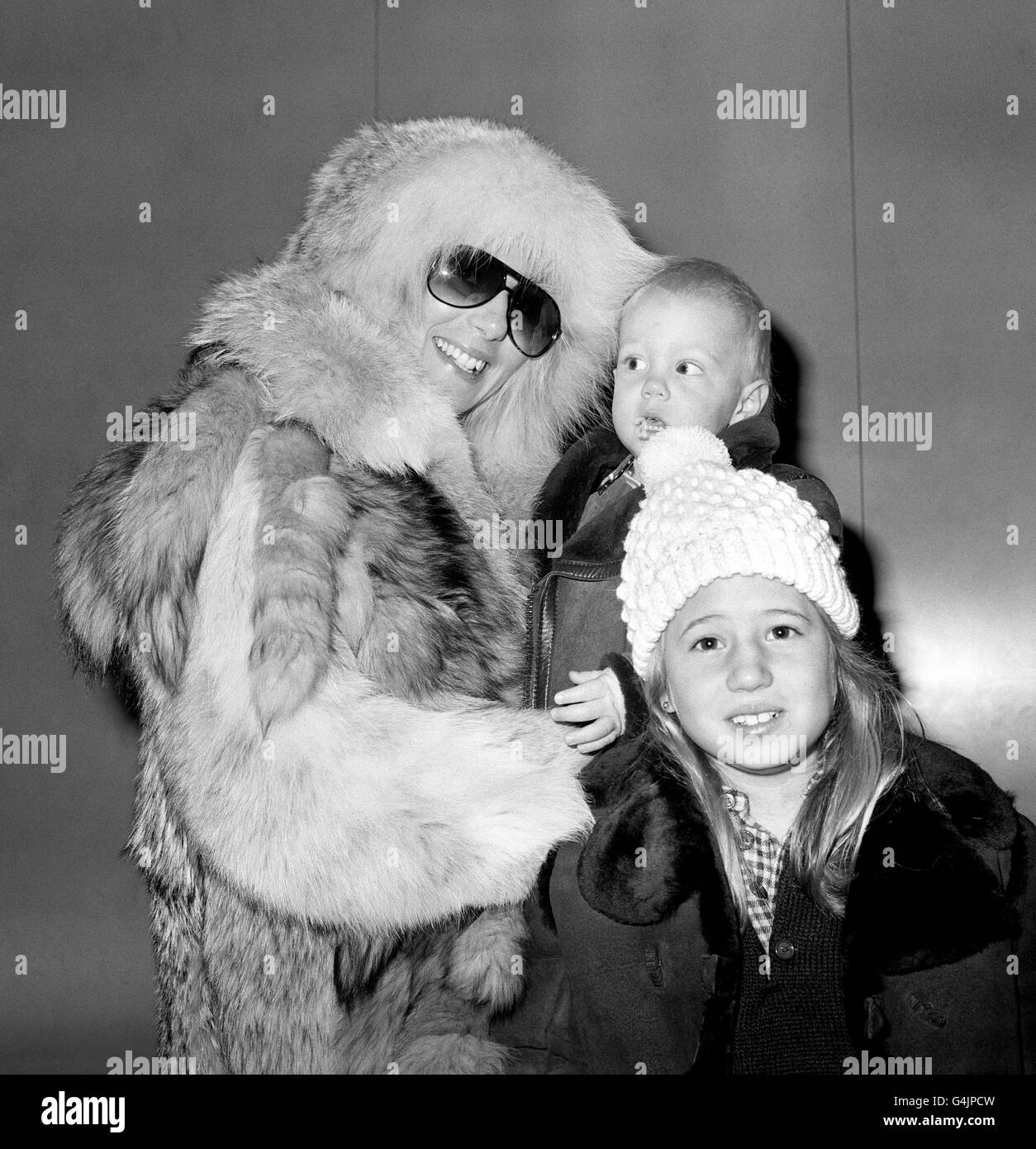 Singer Cher, barely recognisable in fur hat and sunglasses, at Heathrow Airport with her children: Chastity, 8, her daughter from her marriage to Sonny Bono, and 18-month-old son Elijah Blue from her current marriage to singer Gregg Allman. Stock Photo