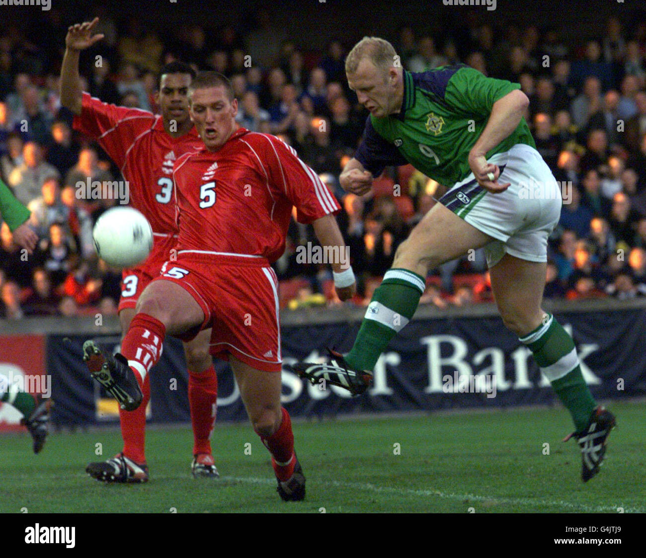 Northern Ireland's Ian Dowie (R) kicks the ball past J Devos (No 5) and B Parker of Canada, during their international friendly football match at Windsor Park, Belfast. Stock Photo