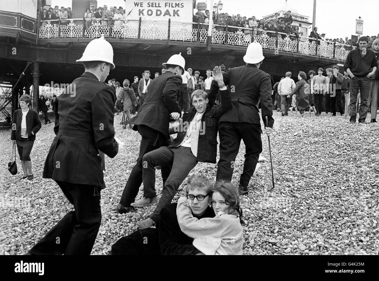 White-helmeted Brighton police arresting youths during fighting between Mods and Rockers and the police on Brighton beach. Stock Photo