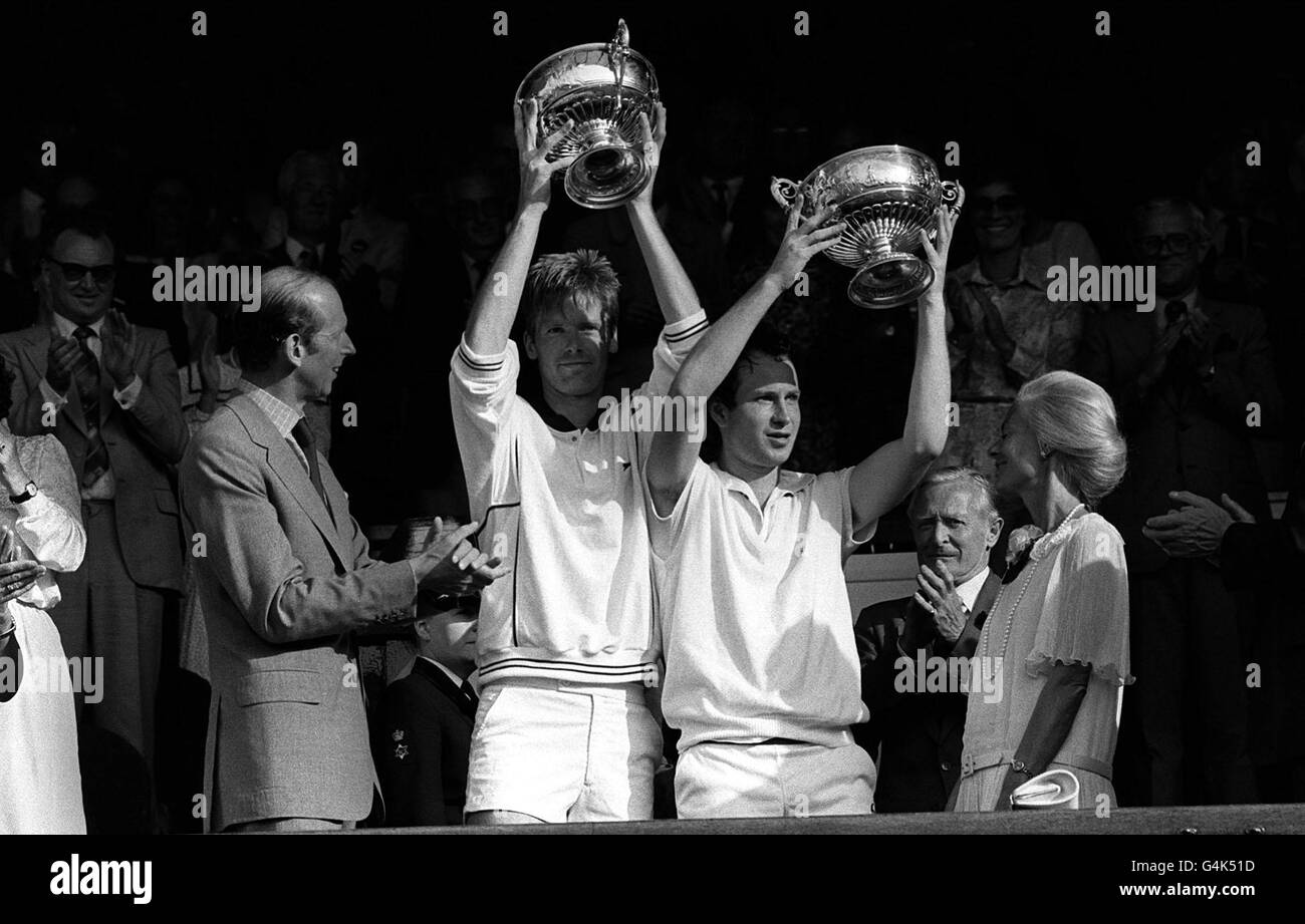 American tennis players John McEnroe (R) and Peter Fleming hold their trophies aloft, which were presented to them by the Duke and Duchess of Kent, after they won the the men's doubles title at Wimbledon. They beat Australian pair Paul McNamee and Pat Cash. Stock Photo