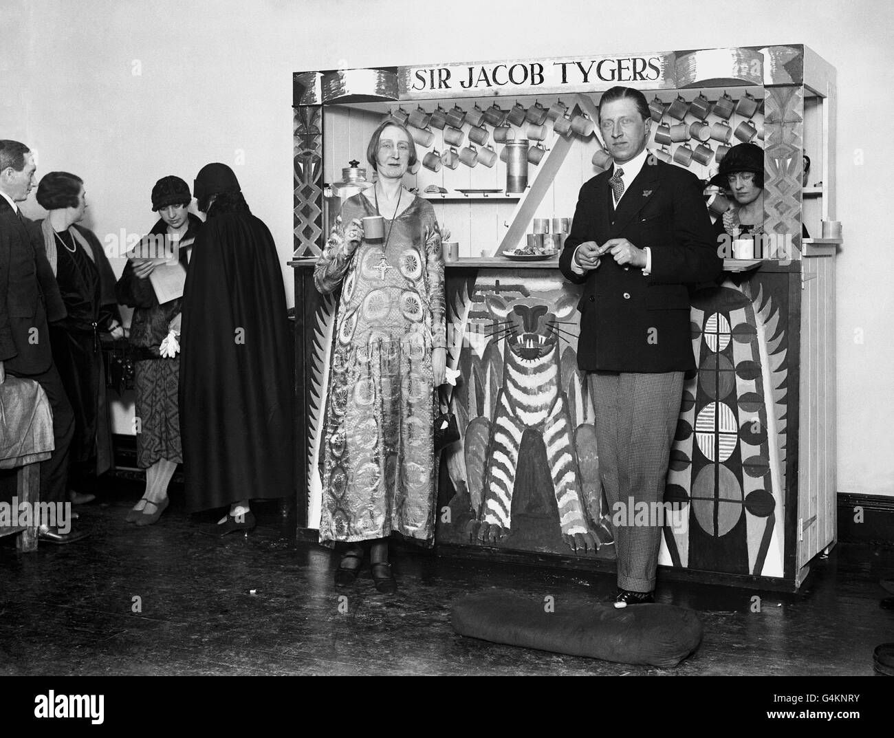 The novel and artistic 'Jazz' coffee stall which is a feature at the 'At Homes' of the Arts League of Service at Robert Street, Adelphi. Miss Edith Sitwell and her brother Osbert are seen taking refreshment. The gentleman on the extreme left is William Walton. Stock Photo