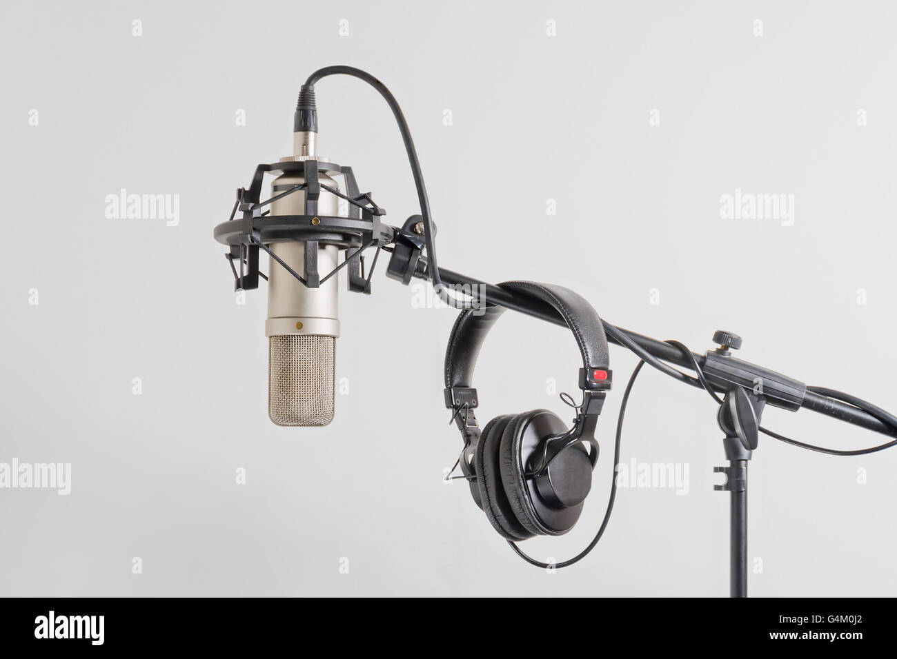 Professional condenser microphone with headphones on a stand. White background. Stock Photo