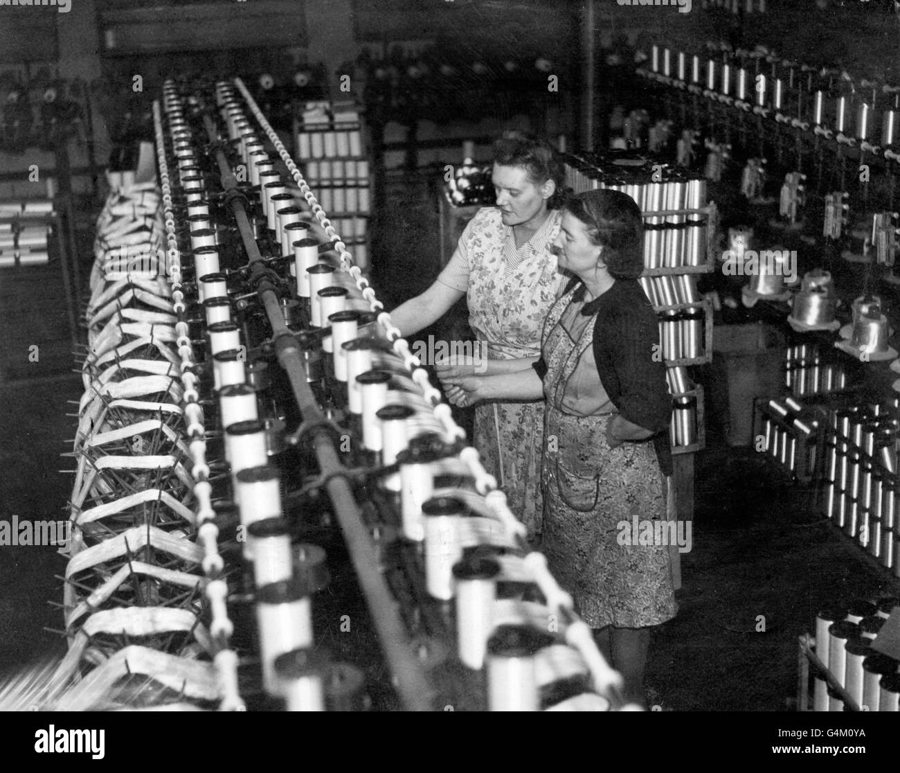 Shift leader Emily Jackson (nearest camera) assists Florance Jones on the winding machine at the silk spinning mill of Bullock Thornhill and Sons, Macclesfield Stock Photo