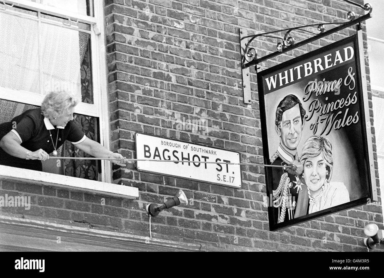 Mrs Vi Lee, landlady of London pub the Prince and Princess of Wales, dusts her swinging pub sign from an upstairs window, to celebrate the Royal wedding of Lady Diana Spencer to the Prince of Wales. Stock Photo