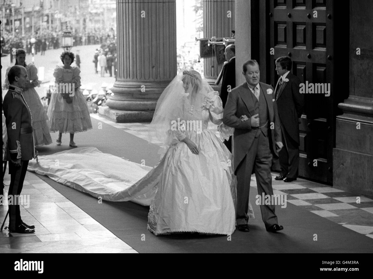 Lady Diana Spencer arrives at St. Paul's Cathedral in London with her father, Earl Spencer, for her wedding to the Prince of Wales. Lady Spencer is wearing a wedding dress with 25ft long detachable train designed by Elizabeth and David Emanuel. *Her veil of ivory silk tulle, spangled with thousands of tiny hand-embroidered mother-of-pearl sequins, is held in place by the Spencer Family diamond tiara. Bridesmaids - India Hicks (right) and Sarah Armstrong-Jones. Stock Photo