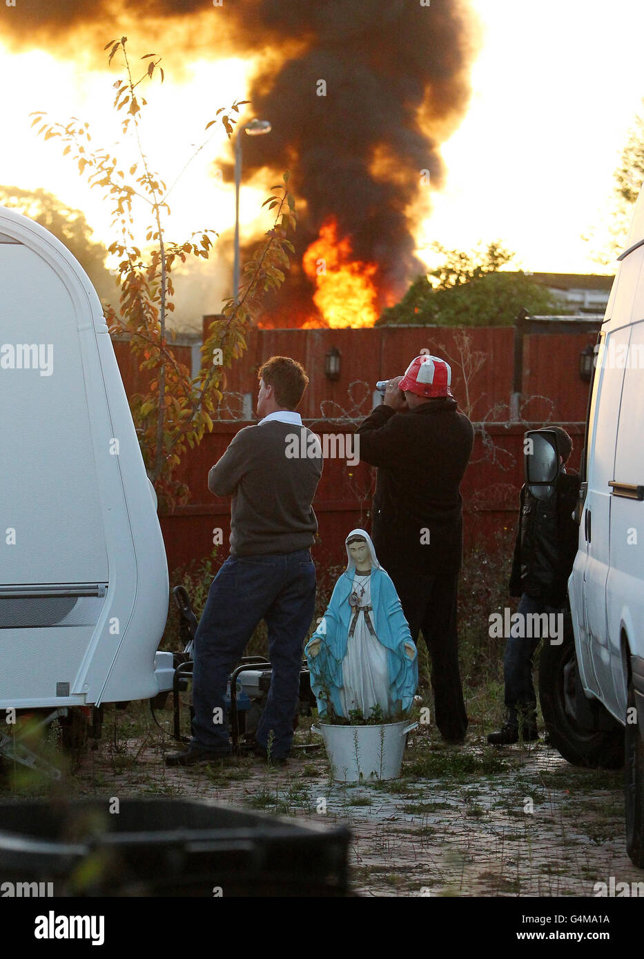 Onlookers watch as smoke and flame rise from Dale Farm in Essex where supporters have clashed with riot police at the UK's largest illegal travellers' site as the planned eviction finally got under way. Stock Photo