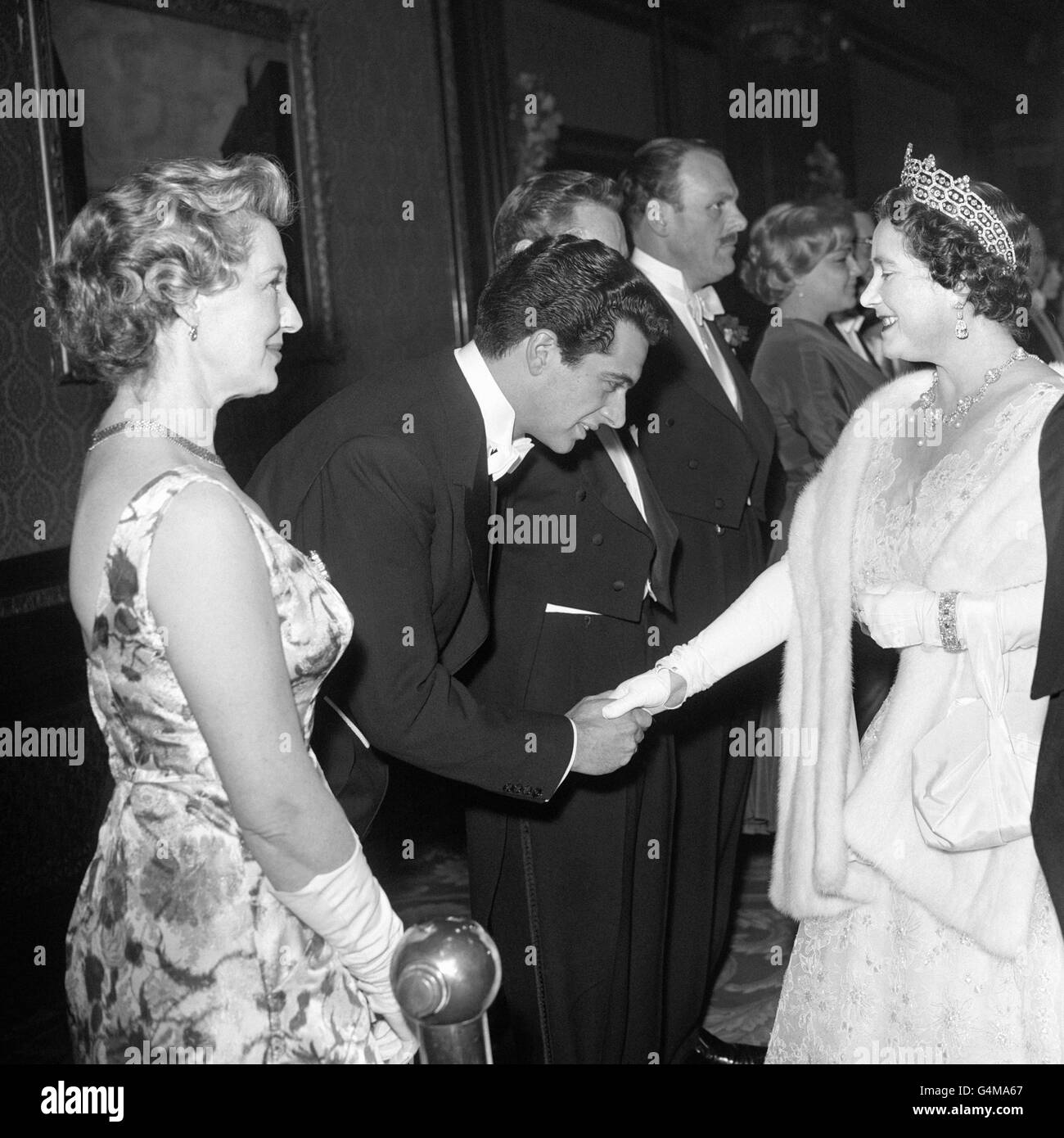 Singer Frankie Vaughan is presented to HRH Queen Elizabeth, The Queen Mother, before the Royal film performance of 'The Horse's Mouth' at the Empire Cinema in London's Leicester Square. Actress Kay Walsh can be seen in the foreground on the left. Stock Photo