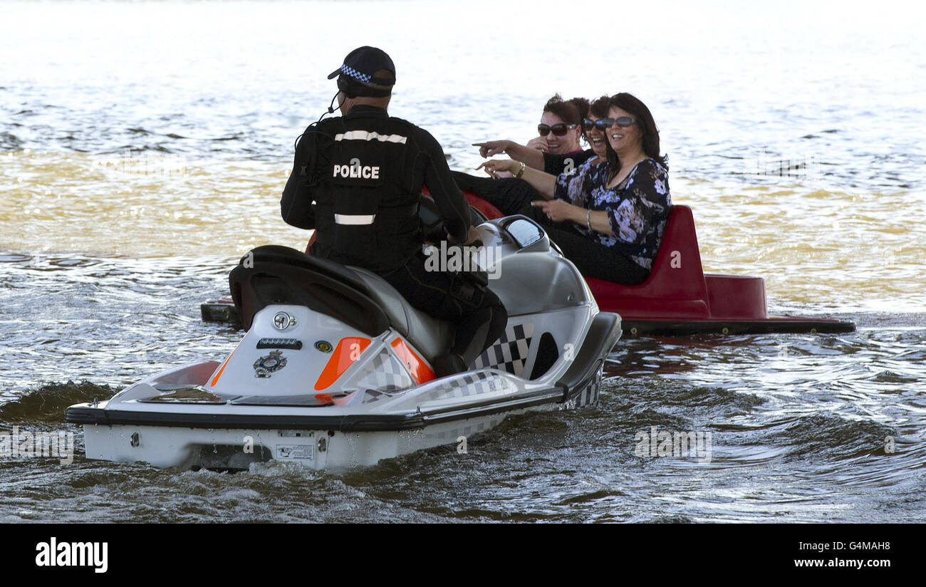 A police officer on a personal watercraft clears people from the route used by Queen Elizabeth II and the Duke of Edinburgh who were travelling on an Australian Navy barge during a trip on Lake Burley Griffin in Canberra during the second day of the Royal couple's 11 day visit. Stock Photo