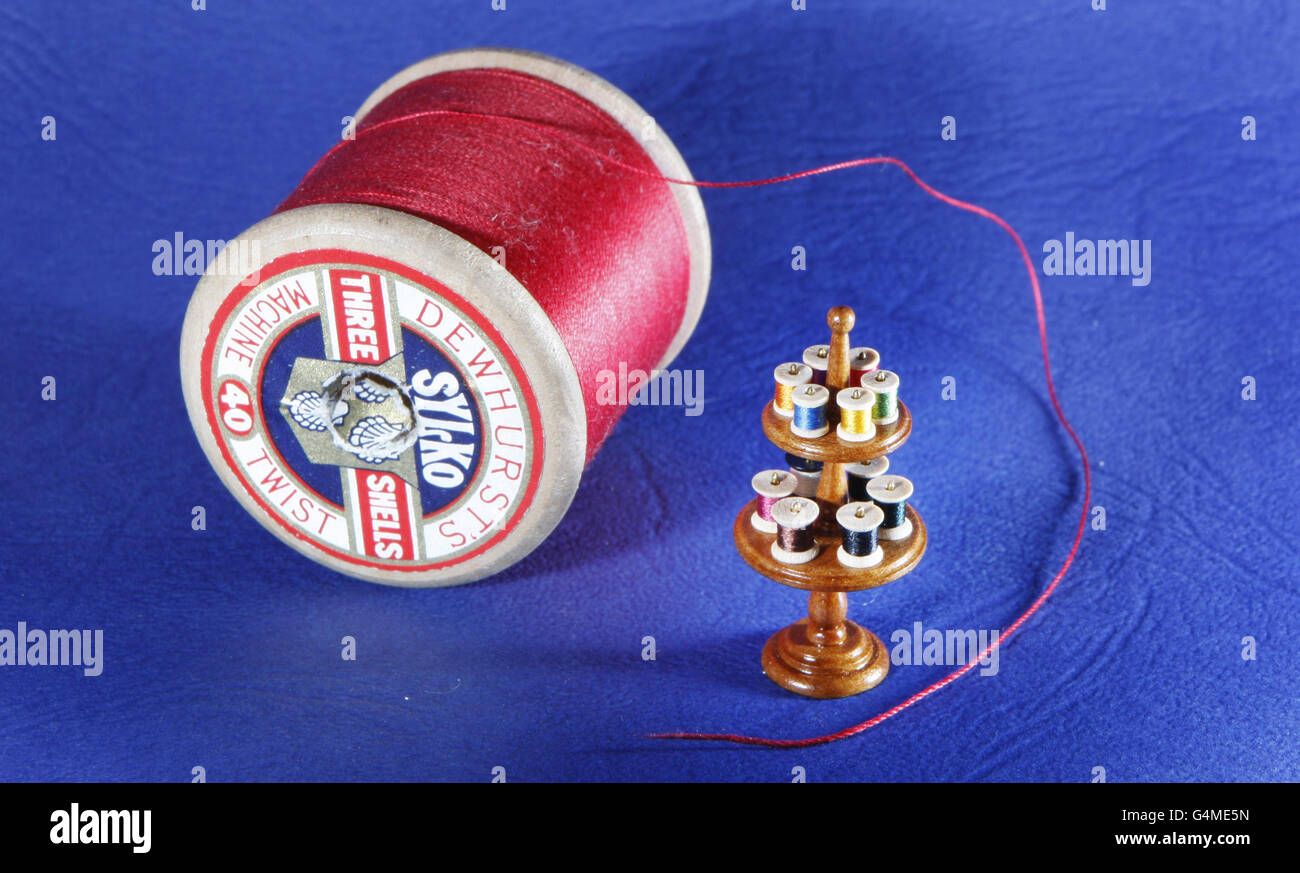 A cotton reel is pictured next to a miniature 12 Spool Cotton Reel