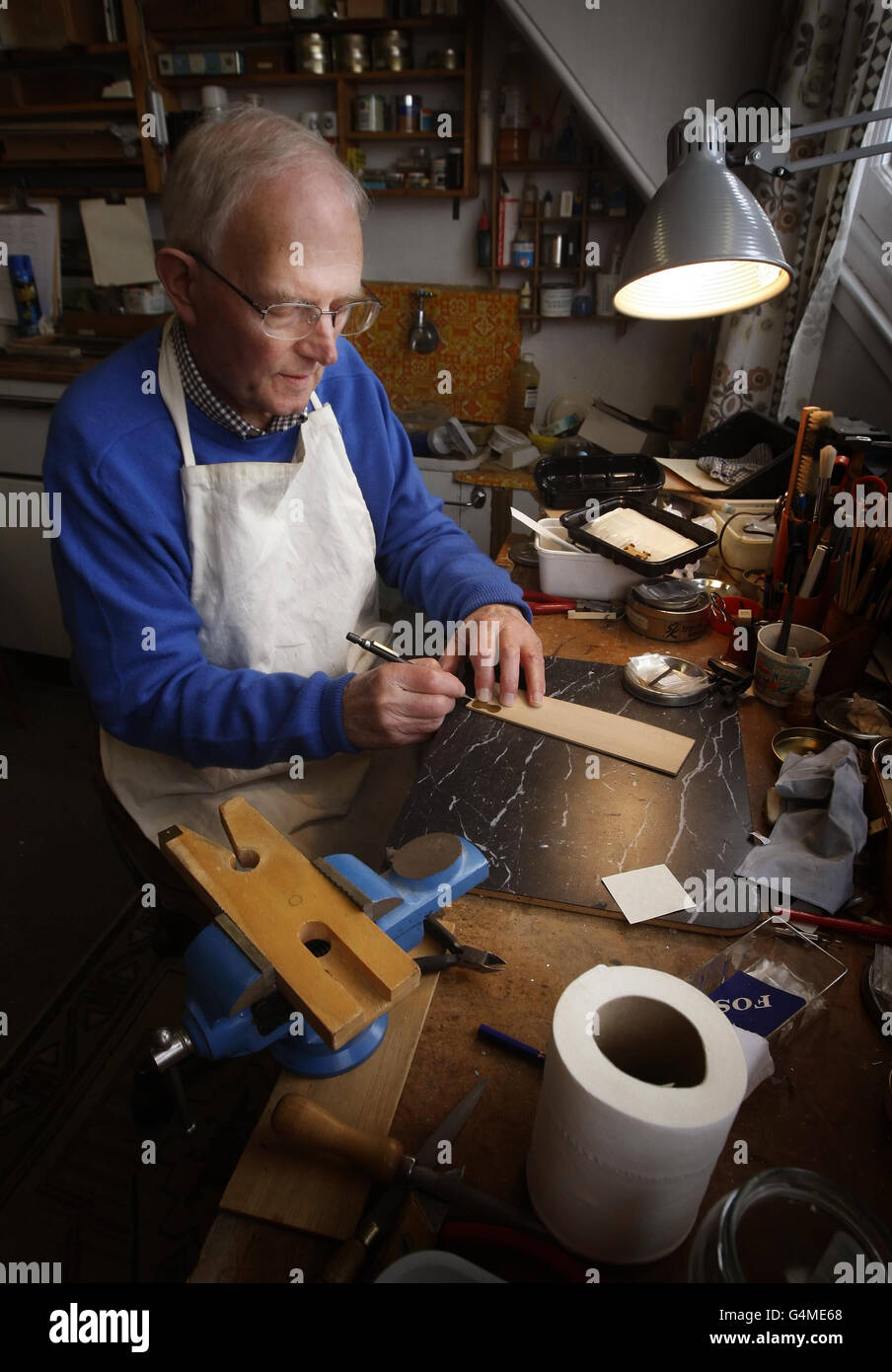 Former Royal Philharmonic Orchestra Cellist David Edwards uses a homemade brass template to draw a violin design on Pearwood at his home workshop in Edinburgh. David has produced a 1000 dolls house violin and bow based on a Stradivarius, and built from Pearwood and Ebony with real sheep gut strings. Stock Photo