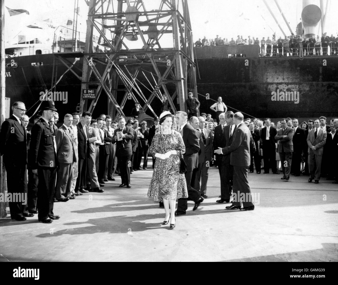 Men line the rail of the ship to share a view of the Queen at the Royal Albert Dock, London, during her visit to the Port of London with the Duke of Edinburgh. Stock Photo