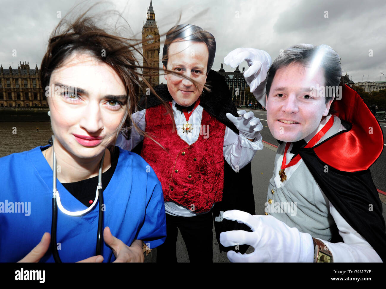 Two Unison's demostrators with David Cameron and Nick Clegg masks dressed as vampires, during a photocall on Westmister Bridge in central London, take a 'bite' out of public sector worker to highlight the union's claim that one in five people will suffer if the government carries out its public sector pension reform. Stock Photo