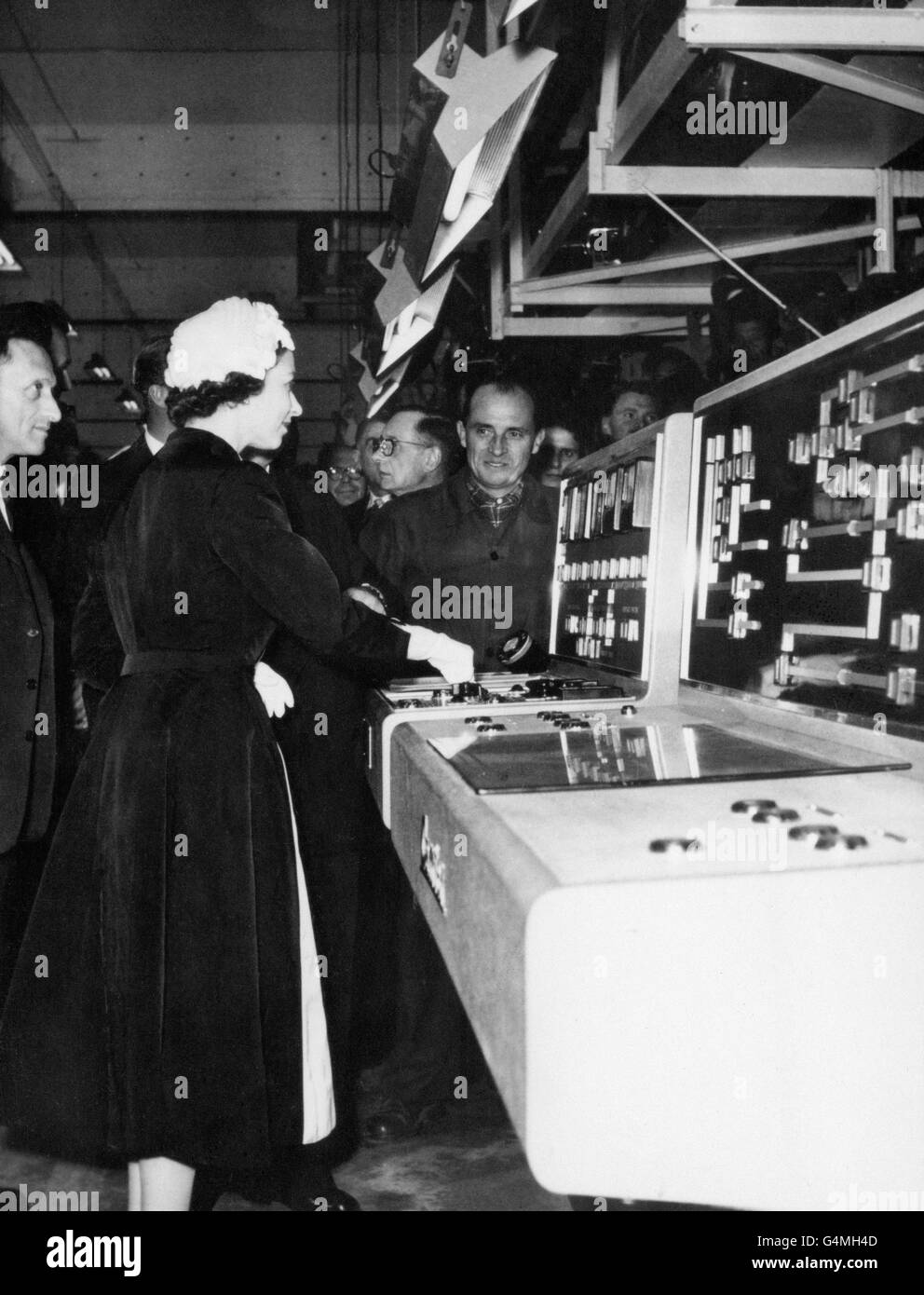 Queen Elizabeth II presses a button on a control panel and brings the production lines to a stop during her visit with the Duke of Edinburgh to the Renault car factory at Flins. Stock Photo