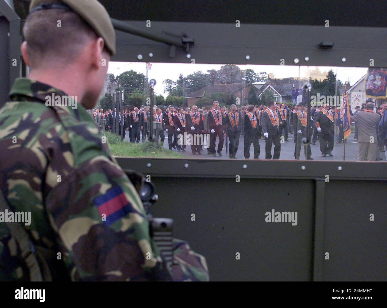 A British Guardsman keeps a watch on Orangemen from behind a security