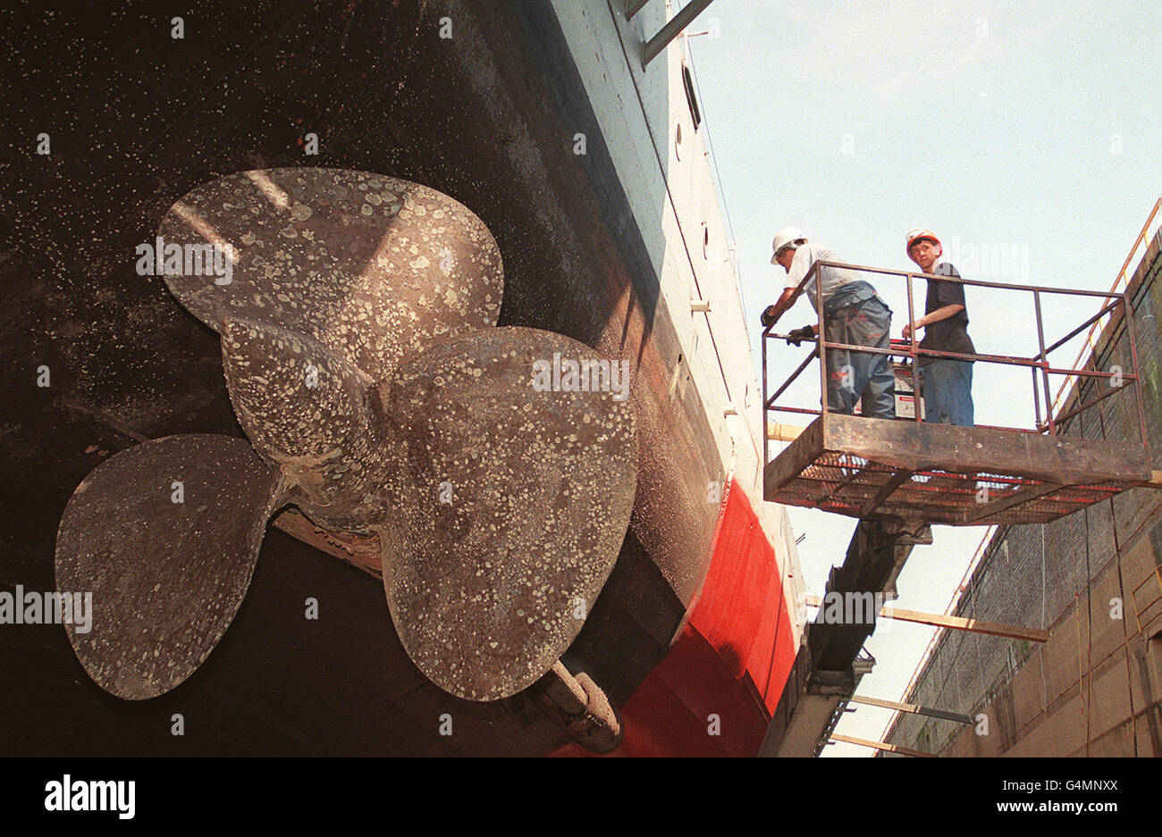 A workers check the propeller on the cruiser HMS Belfast whilst it is in dry dock in Portsmouth naval base for a re-fit. The cruiser, which last saw service in the late sixties, has not been in dry dock for18 years. Stock Photo