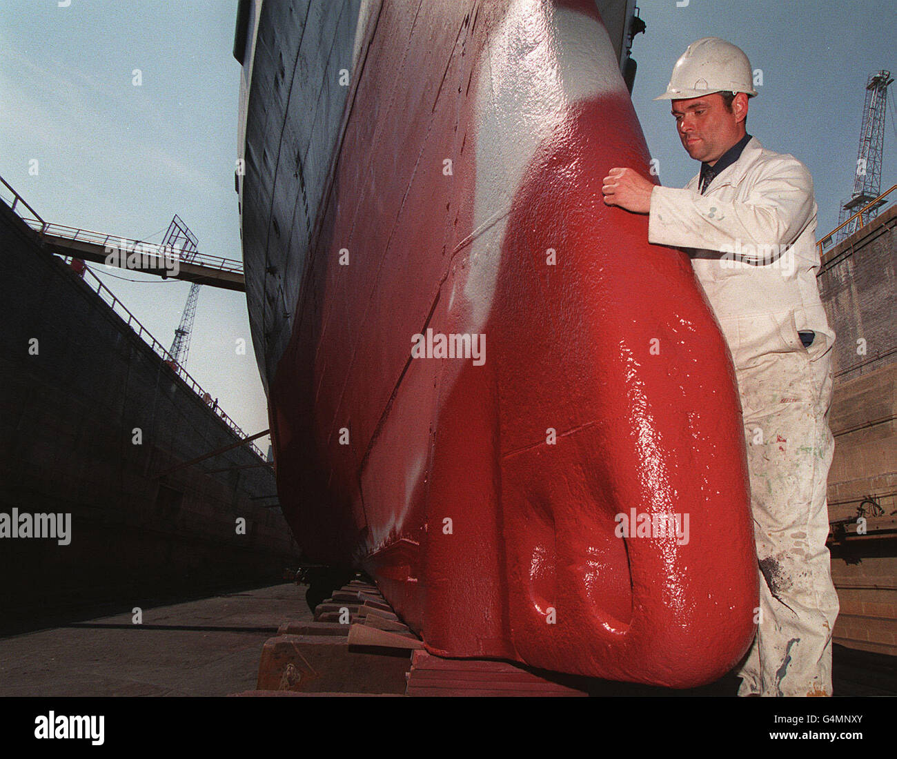 A worker checks the paint depth on the cruiser HMS Belfast whilst it is in dry dock in Portsmouth naval base for a re-fit. he cruiser, which last saw service in the late sixties, has not been in dry dock for18 years. Stock Photo