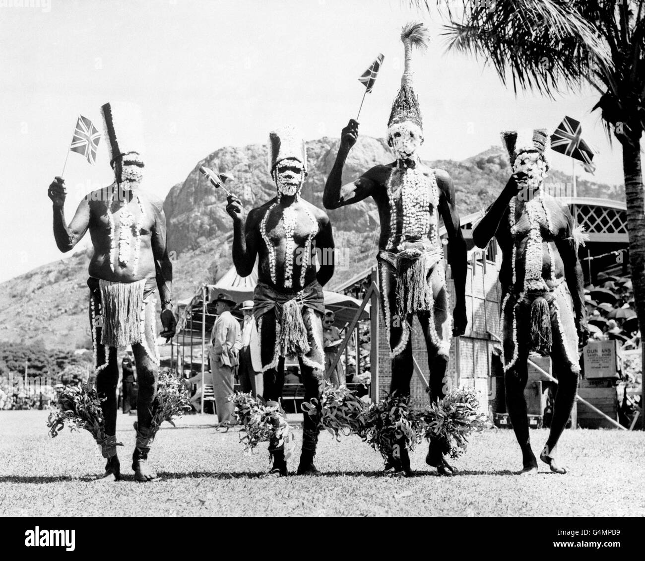 Aborigines wave union jack flags as they wait to see Queen Elizabeth II, during her tour of Australasia. Stock Photo