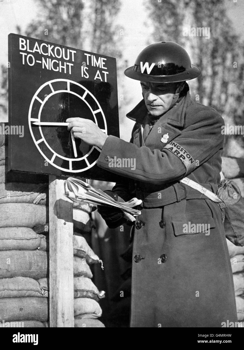 An air-raid warden sets a black-out time clock indicator at an A.R.P. post near London during the Second World War. Stock Photo