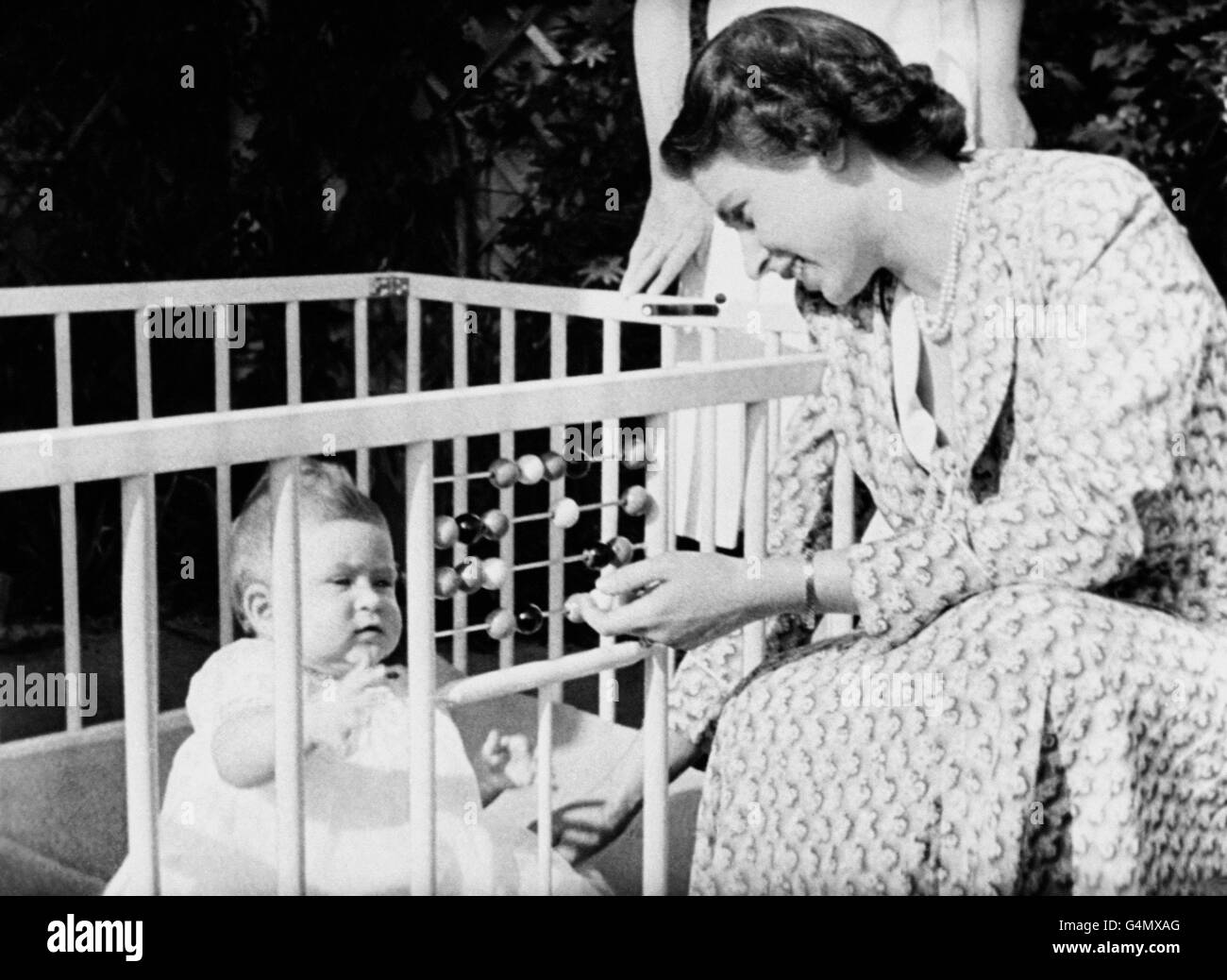 Queen Elizabeth II with her baby Prince Charles in the grounds of