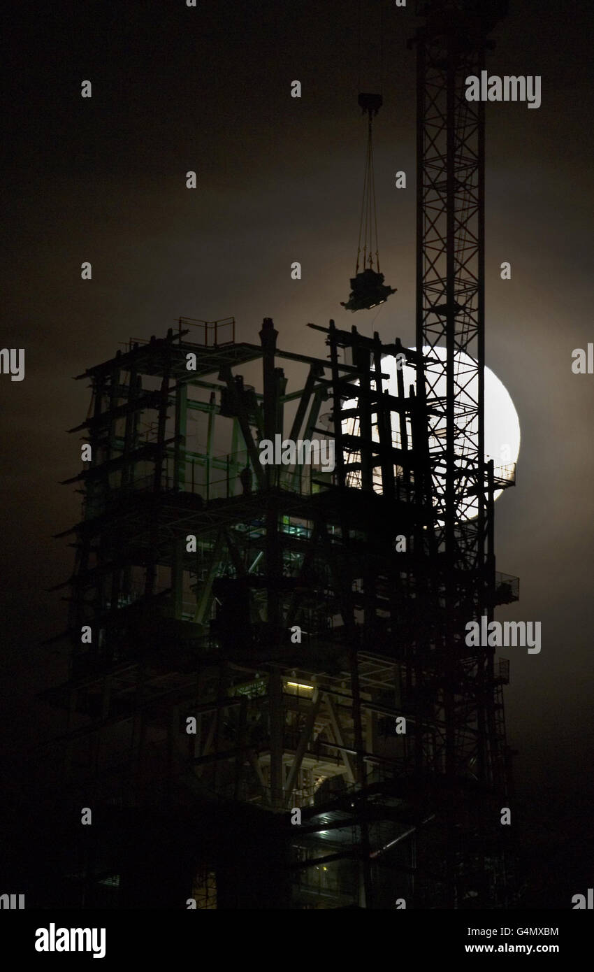 A silhouette of a workman as the full moon is seen above the Shard building, London. Stock Photo