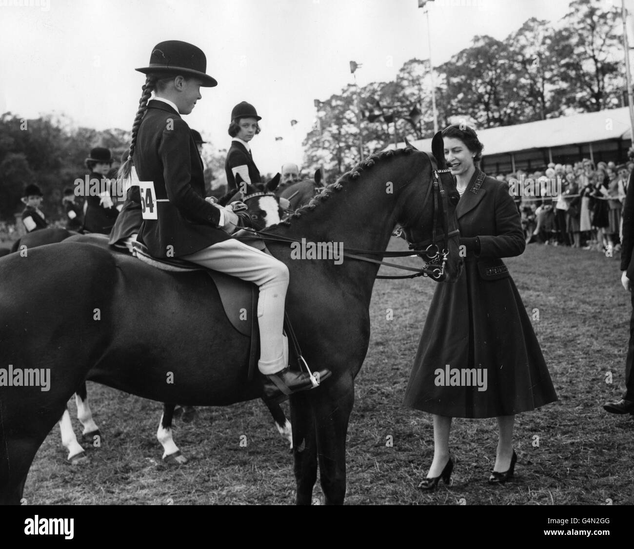 Queen Elizabeth II presents an award to Jabeena Maslin, on 'Criban Biddy Bronze', after winning the Child's Pony Event at the Royal Windsor Horse Show at Home Park, Windsor Castle. Stock Photo
