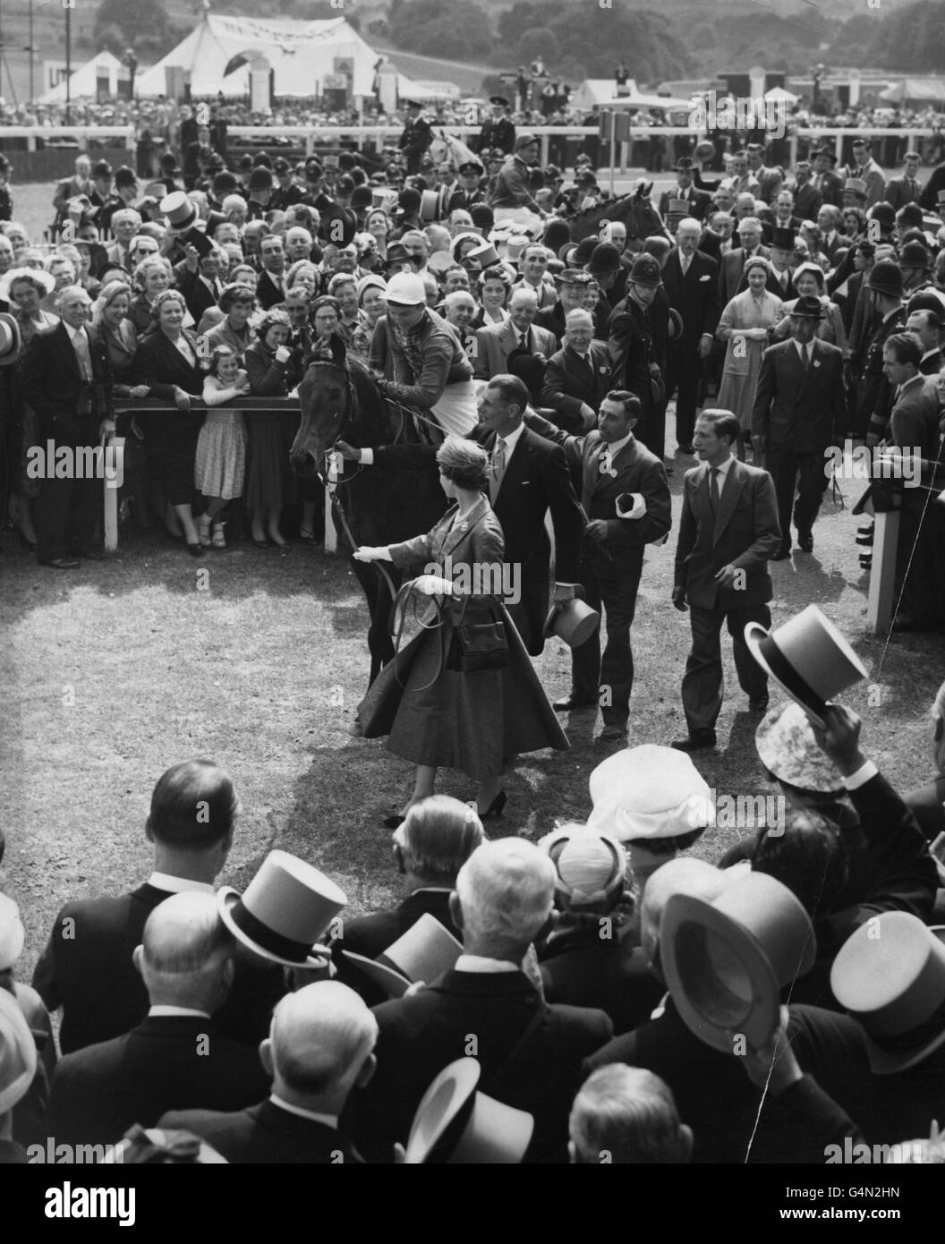 Horse Racing - The Oaks Stakes - Epsom Racecourse. Queen Elizabeth II leads in the winner of The Oaks, her own filly Carrozza, which had been ridden to victory by Lester Piggot at Epsom. Stock Photo