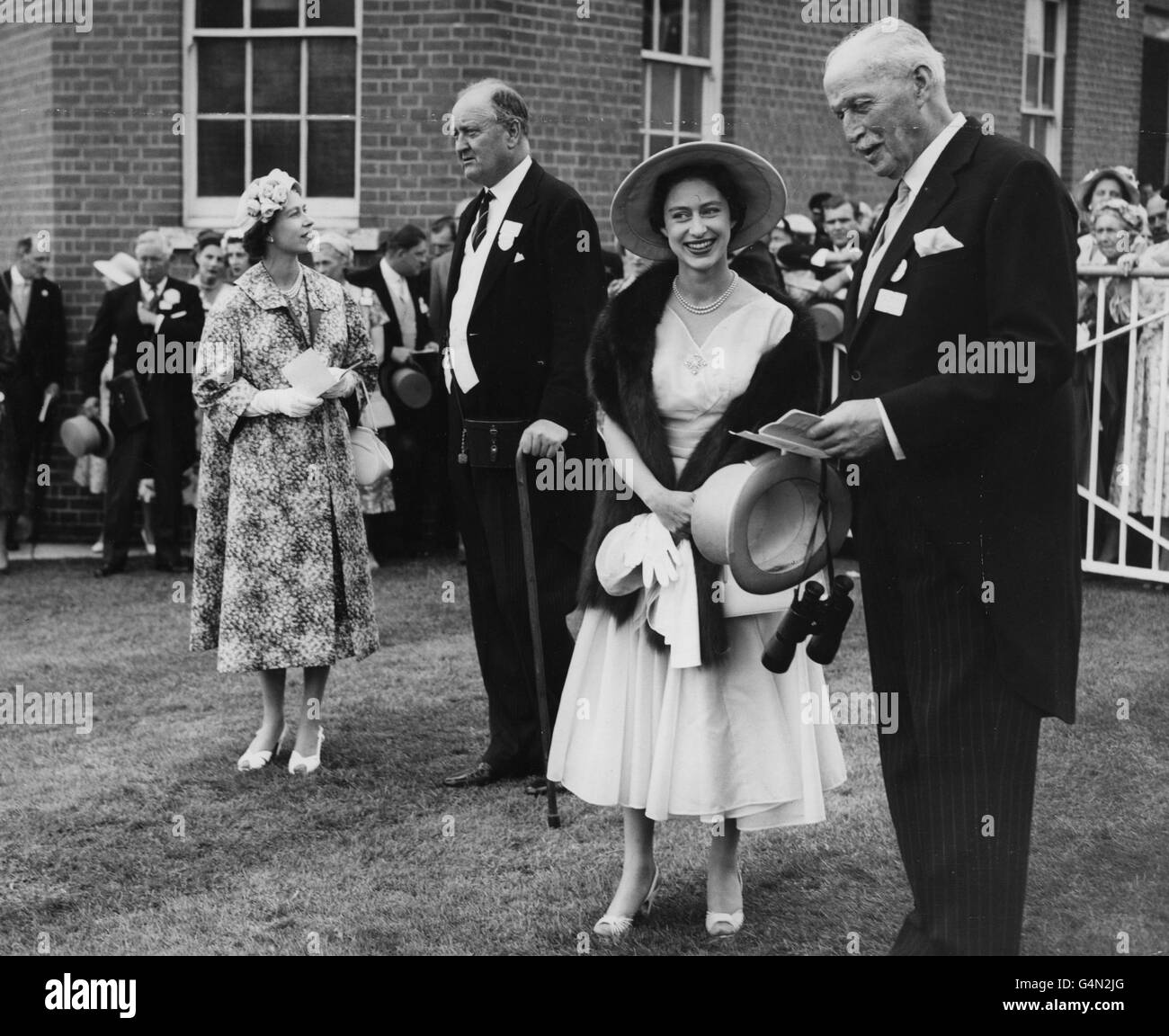 Queen Elizabeth II talks with her trainer, Captain Cecil Boyd-Rochfort, as Princess Margaret talks with the Queen's racing manager Captain Charles Moore, after the Queen's filly, Almeria, had won the Ribblesdale Stakes at the Royal Ascot meeting. Stock Photo