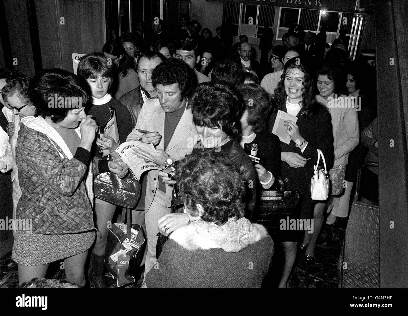 Welsh singer Tom Jones signs autographs for fans who gathered at London's Heathrow Airport before he flew out to Miami on the first leg of his five-month American tour. Stock Photo