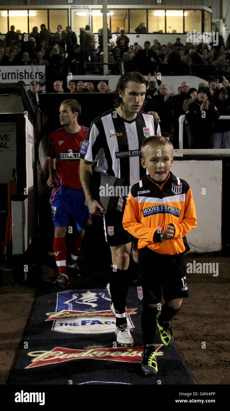 Soccer - FA Cup First Round Replay - Bath City v Dagenham and Redbridge - Twerton Park. Bath City captain Joe Burnell (back right) leads his team out onto the pitch along with a mascot (front) Stock Photo