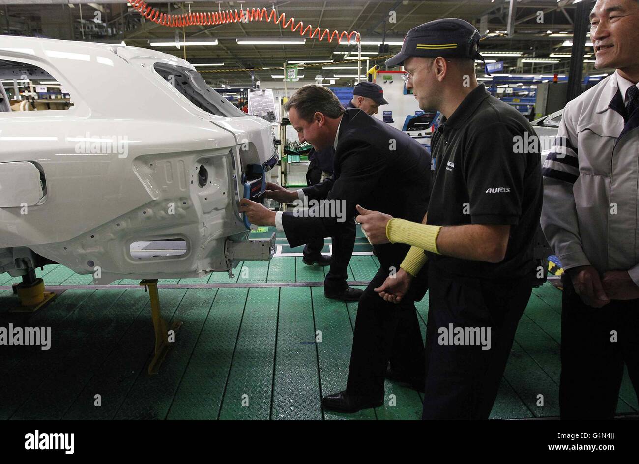 Prime Minister David Cameron installs a badge on a car at the Toyota factory in Burnaston. Stock Photo
