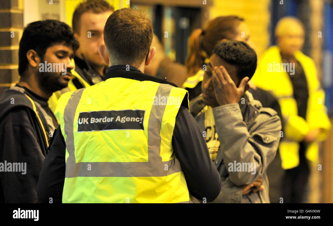 A UK Border Agency official with staff and customers at Bestway Cash and Carry in Liverpool before they are questioned during a UK Border Agency raid. Stock Photo