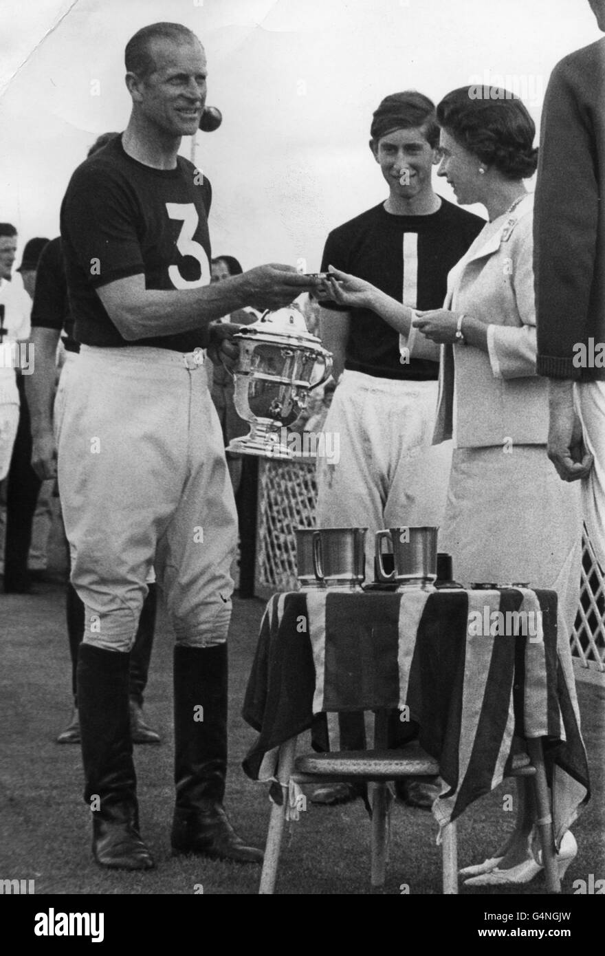 The Duke of Edinburgh receives the Westbury Cup and an ashtray from the Queen, with Prince Charles looking on, at Windsor. The Duke scored two goals and Prince Charles notched one in the Rangers' 7-2 victory over Bishops. Stock Photo